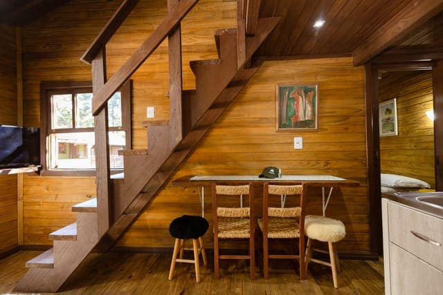 Sala de jantar de chalé em madeira, com escada para o mezanino