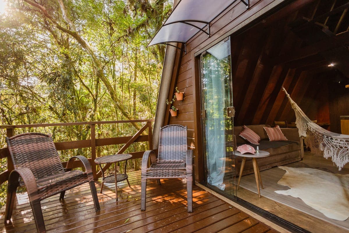 Deck e interior integrados, com rede e vista para as árvores